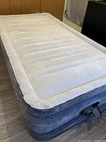 Inflated twin air mattress showing flocked surface and raised sides with built-in pump visible