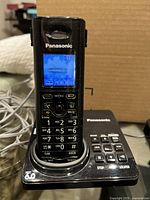 Handset on digital answering base showing lit LCD screen