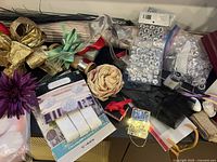 Tabletop view of assorted party décor items: ribbons, artificial flowers, gem packs, lights