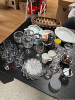 Overview of assorted glassware, ceramics, stainless items and wicker basket on table