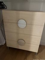 Front view of three-drawer light wood dresser with circular metal handles