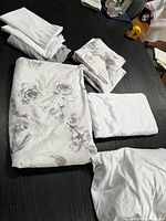 Folded twin floral duvet cover and matching linens on table