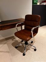 Front angled view of brown leather desk chair at desk