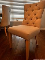Front view of light grey tufted dining chair with wooden legs