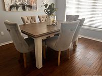 Dining table with six chairs around it, top view of wood surface and white legs