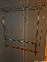 Hanger units installed under wire shelf showing mounting hooks and dual rods