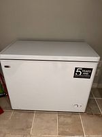 Front view of white chest freezer with warranty sticker and control dial