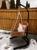 Full view of rattan egg chair on black steel stand outdoors