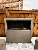 Full front view of rectangular propane fireplace against fence, snow on ground