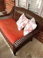 Front angle of wicker loveseat with cushion and pillows