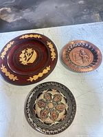 Three engraved decorative wall plates grouped on table