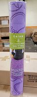 Rolled Gaiam Wildflowers lavender yoga mat in packaging