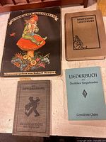All four German songbooks arranged on table