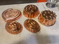 Top view showing five of the six polished copper molds displaying shape variety and finish