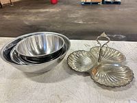 Nested set of four stainless steel bowls beside three-section shell tray
