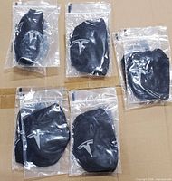 Ten individually bagged black masks showing Tesla logo