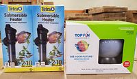 Front view of two boxed Tetra 50W heaters and boxed Top Fin ColorFlow aeration decor