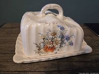 Front view of domed cheese dish on tray showing floral design and handle