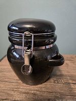 Front view of black ceramic canister with closed clamp lid