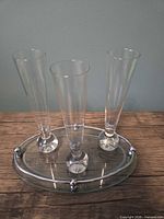 Front view of three clear glass bud vases on oval tray