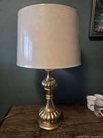 Full view of brass table lamp with cylindrical beige shade
