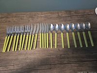 Full 23-piece cutlery set laid out: 8 forks, 7 knives, 8 spoons