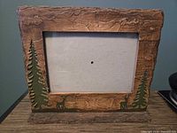 Front of rustic bark-look frame with tree and deer carvings