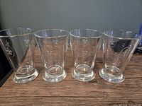 Front view of four matching clear glass cups standing upright