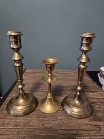Front view of three brass candlesticks showing relative heights and design details