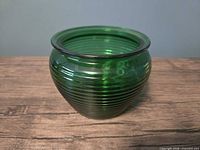 Front view of emerald green ribbed glass candle holder showing overall shape and ribbing
