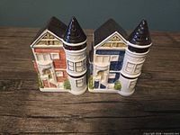Front view of both house-shaped shakers showing red and blue facades, windows, doors, turret roofs
