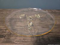 Top view of round yellow depression glass cake plate showing scalloped rim and foot placements