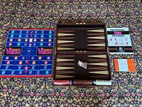 Both games laid out: backgammon case open with pieces, Vegas Pigskin board, two rule books