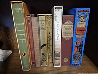 Group shot of all eight Folio Society books on shelf showing spines and some slipcases