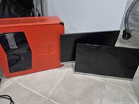 Red computer case alongside two monitors