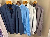 Four shirts hanging on hangers showing colours and styles