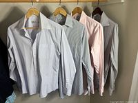 All four shirts hanging on wooden hangers
