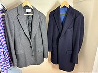 Grey Sandro jacket and navy Spier & Mackay overcoat hanging side by side