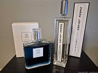 Both Serge Lutens perfume bottles with their boxes on a surface
