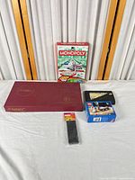 All five boxed items displayed: Monopoly Grab & Go, Scrabble, dominoes, LEGO 3365, magic coin trick