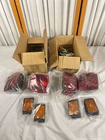 Two open boxes with bundled wire harness, brackets, red tail lamps and amber marker lamps still in plastic