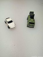 White sports car beside green missile truck