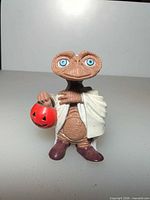 Front view of E.T. figurine holding pumpkin pail