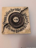 Front view showing ivory base, bronze push button, printed phrase