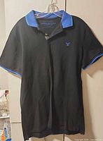 Full front view of black polo shirt on hanger