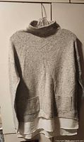 Front view of grey Camber & Grace sweater with turtleneck, pockets and white attached hem