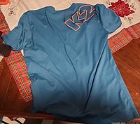 Full front view of blue K2 shirt laid flat on table