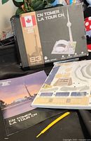 Box front showing CubicFun CN Tower & SkyDome 83-piece puzzle, booklet, sealed panel pack, yellow pick tool