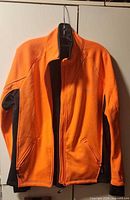 Front view of orange Running Room jacket on hanger