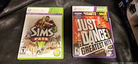 Front view of two Xbox 360 game cases: The Sims 3 Pets and Just Dance Greatest Hits